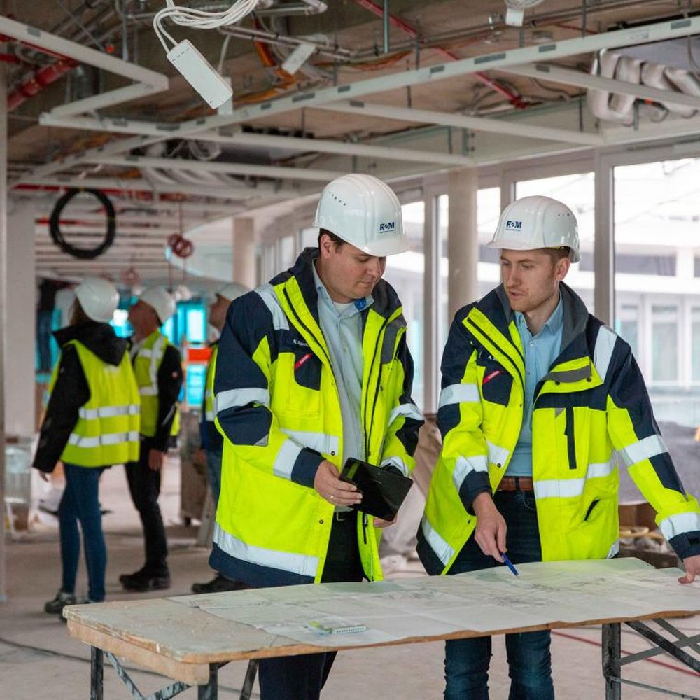 Zwei Techniker besprechen Baupläne auf der Baustelle